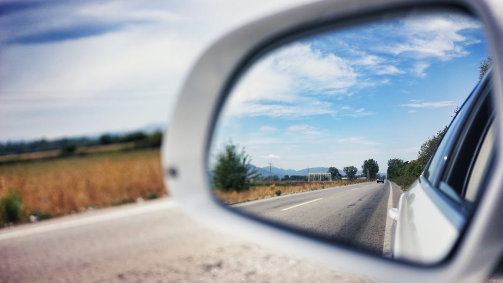 A side-view mirror reflects a road